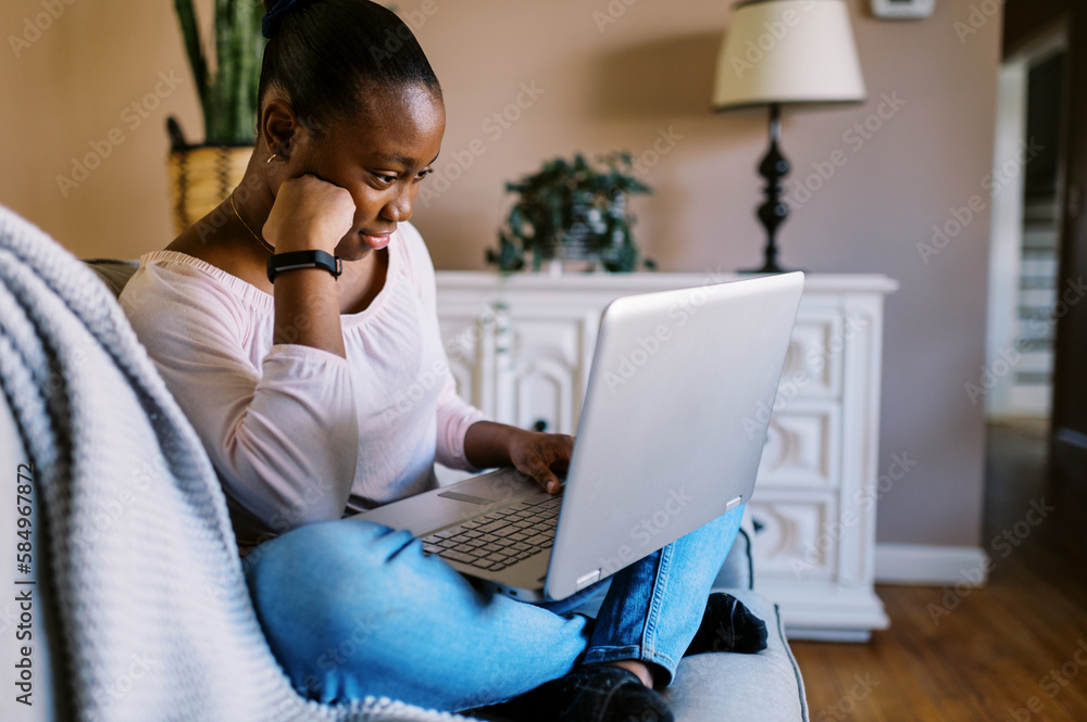 black girl sitting on couch in living room doing homework on laptop black girl sitting on couch in living room doing homework on laptop
