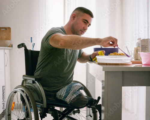 A man without legs in a wheelchair cooks in his kitchen  photo