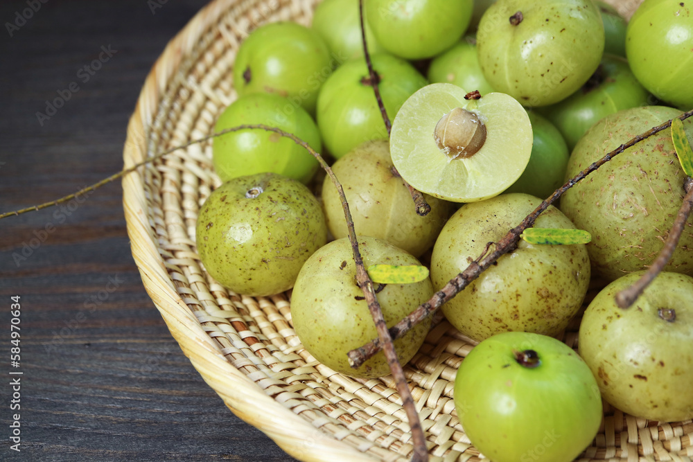 Heap of Fresh Indian Gooseberries or Amla in a Basket on Black Wooden Table Heap of Fresh Indian Gooseberries or Amla in a Basket on Black Wooden Table