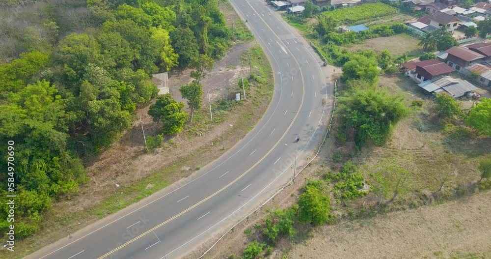 The angle of the drone tracking along the car driving along empty country highway a curved in idyllic rural landscape. The angle of the drone tracking along the car driving along empty country highway a curved in idyllic rural landscape.