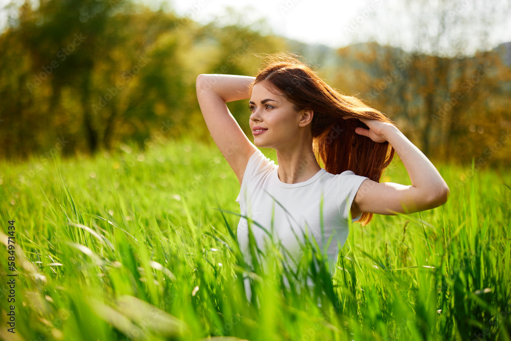 beautiful woman sitting in tall grass adjusting her hair beautiful woman sitting in tall grass adjusting her hair