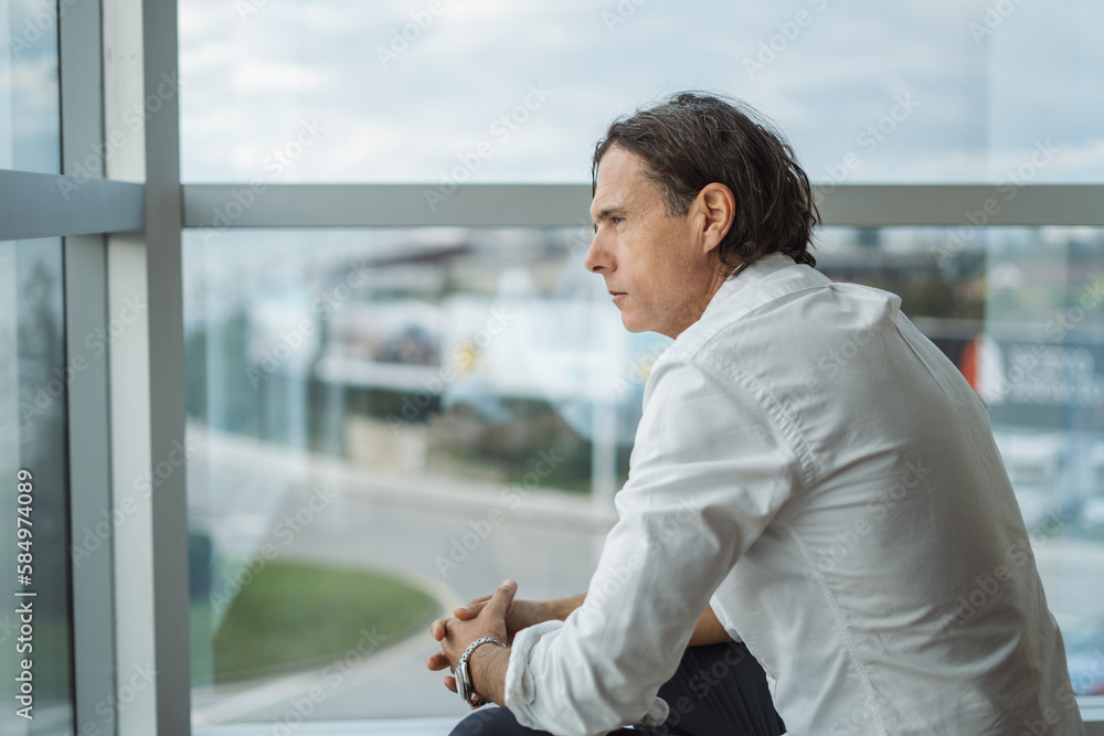 Thoughtful mature boss sitting near hotel window Thoughtful mature boss sitting near hotel window