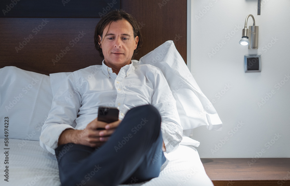Elegant man browsing smartphone on bed Elegant man browsing smartphone on bed