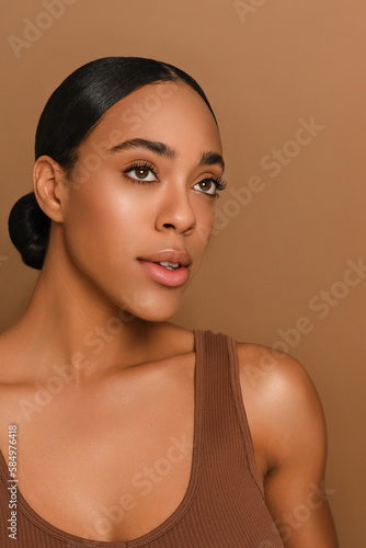 Beautiful African-american model with no make on a solid beige background  beauty shot for a cosmetic or make up brand