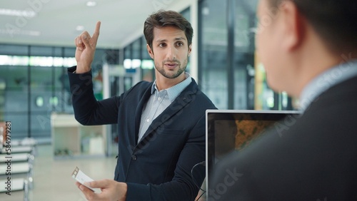 Indian businessman passengers talking with ground staff inquire about travel and flight information holding ticket, boarding pass and passport at airport