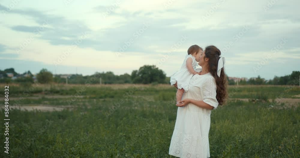 Beautiful mother holding her baby daughter in the summer field Beautiful mother holding her baby daughter in the summer field