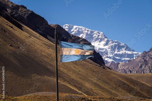 Argentine flag fluttering in the wind, behind the Aconcagua hill photo