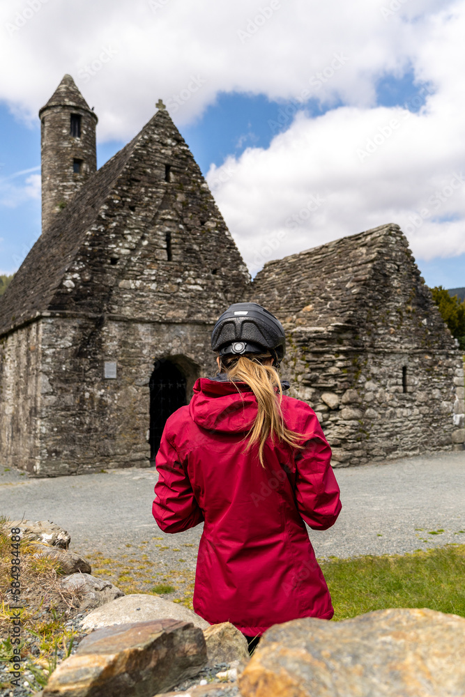 Cyclist woman by the St. Kevin Church in Glendalough