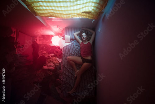 Sleeping woman in cinematic small dark bedroom photo