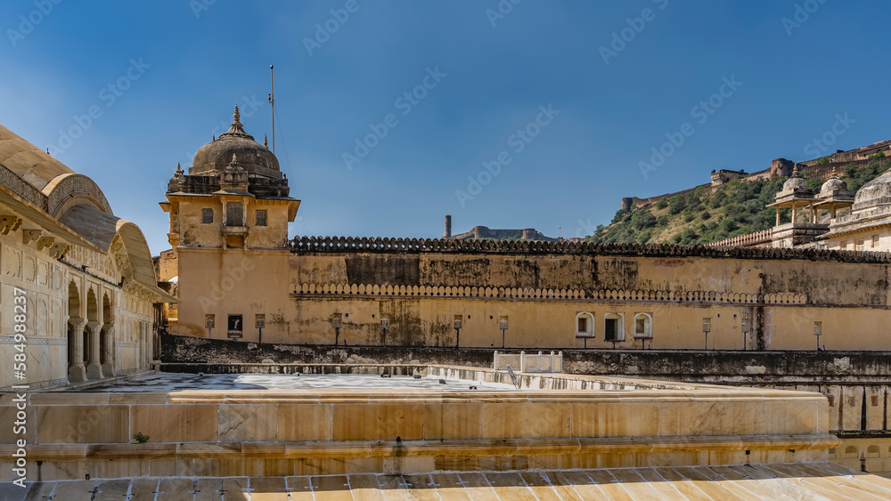The ancient Amber Fort is built of orange sandstone. Weathered fortress walls, domes with spires against the blue sky. India. Jaipur