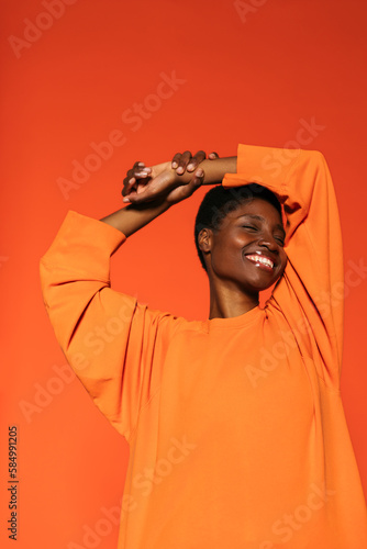 Cheerful woman standing in orange wall photo