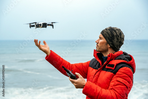 Male explorer operating drone near ocean photo