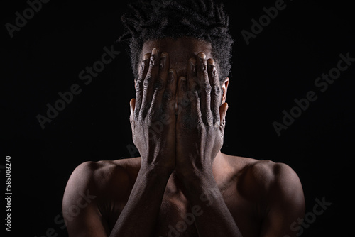 Dramatic Studio Portrait of Shirtless Young African Man Covering Face