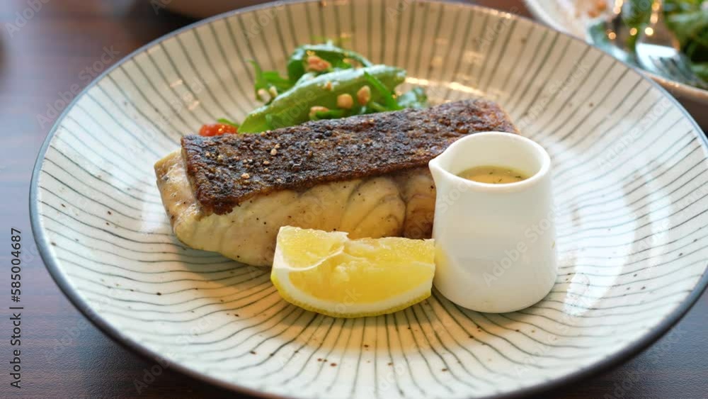 Close up View of Grilled Fish Steak with Lemon Sauce and Salad Close up View of Grilled Fish Steak with Lemon Sauce and Salad