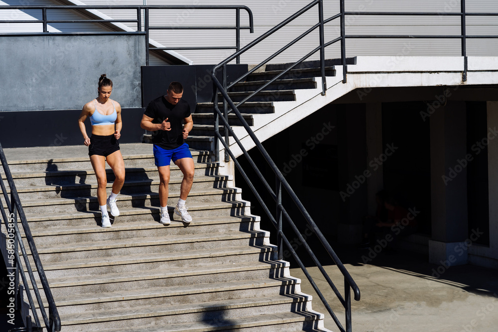 Fototapeta premium Sporty couple running on a stairs in the city