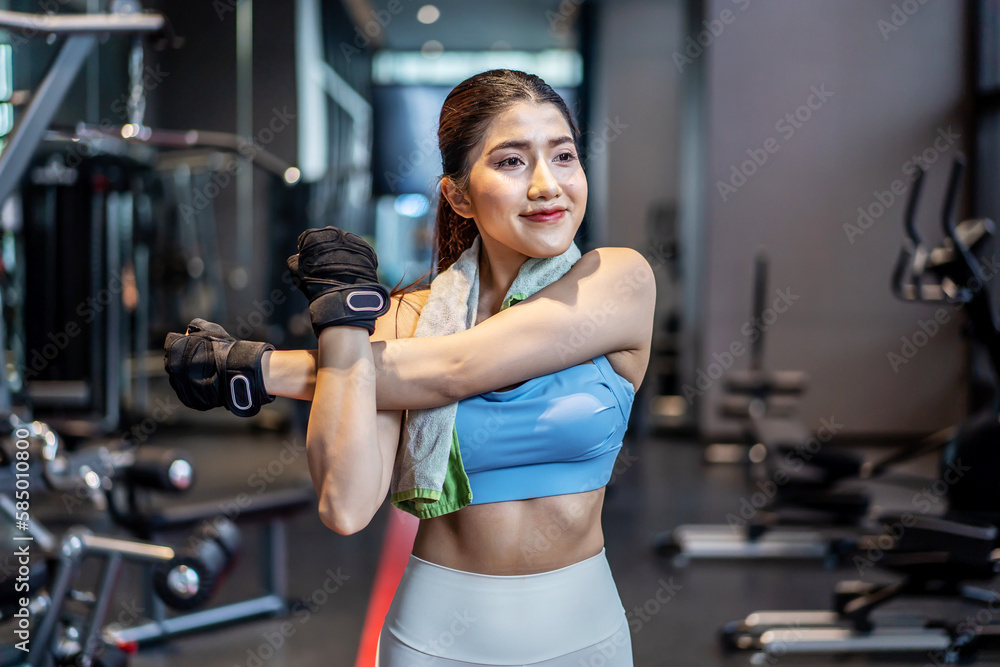 Active young Asian woman stretching her body warm up before intensive workout at gym, basic gym exercises performed by the young female Active young Asian woman stretching her body warm up before intensive workout at gym, basic gym exercises performed by the young female