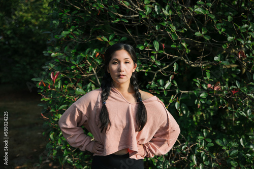 Serious woman in sweatshirt near hedge. photo