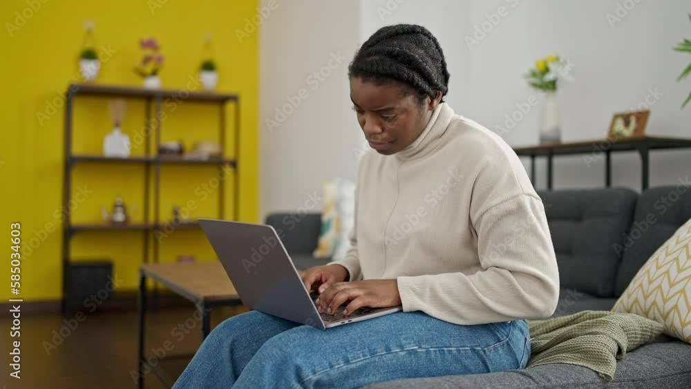 African american woman using laptop sitting on sofa at home African american woman using laptop sitting on sofa at home