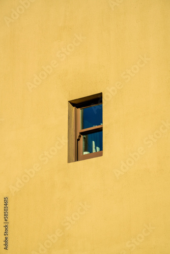Small exterior window in downtown building with brown or beige cement stucco facade in downtown urban area of city © Aaron