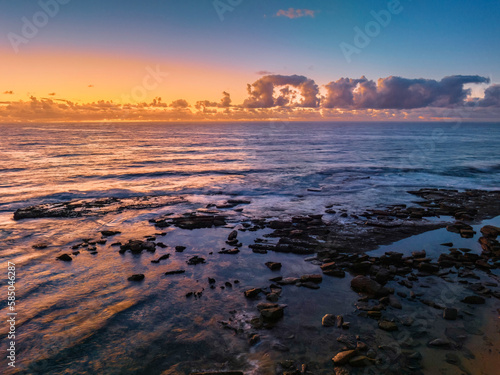 Summer sunrise at the seaside with clouds and rocks © Merrillie