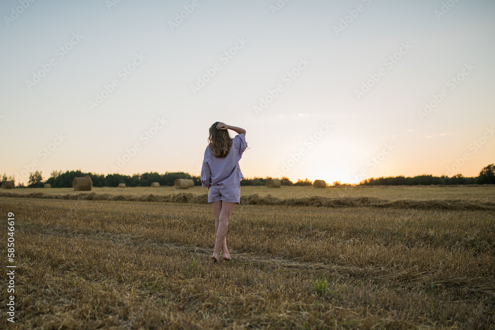 caucasian girl with long hair in a field at sunset looks into the distance, the concept of freedom, space and love for nature