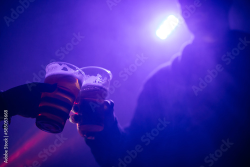 Man and woman cheering with a plastic cup of beer in the nightclub.