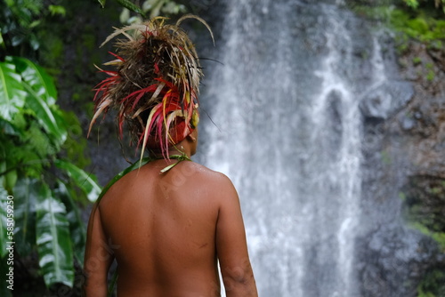 Obraz na plátně A Polynesian man from behind during a traditional ceremony with a waterfall in the background
