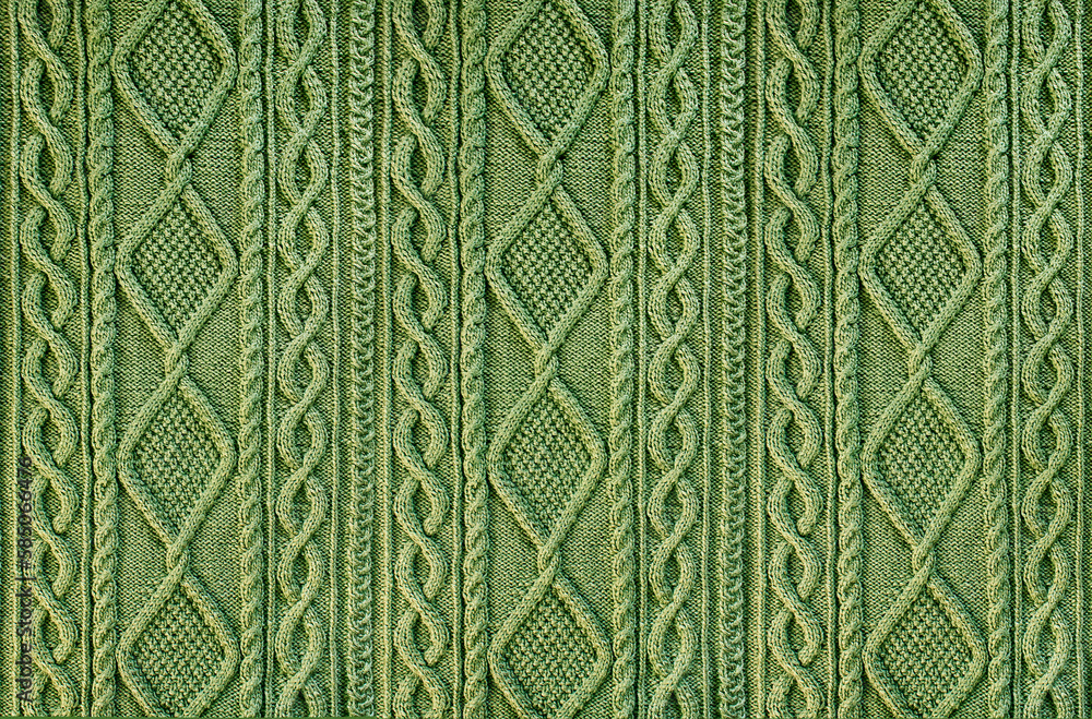 Naklejka premium green background knitted fabric with a pattern. Knitted Arans close-up
