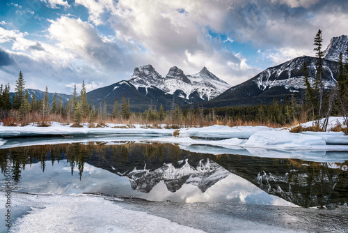 Three Sisters Mountains with snow covered on frozen bow river reflection in the morning on winter