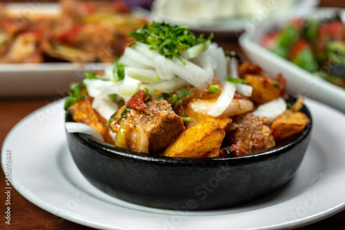 Beef stew with potatoes, carrots and herbs on black background with copy