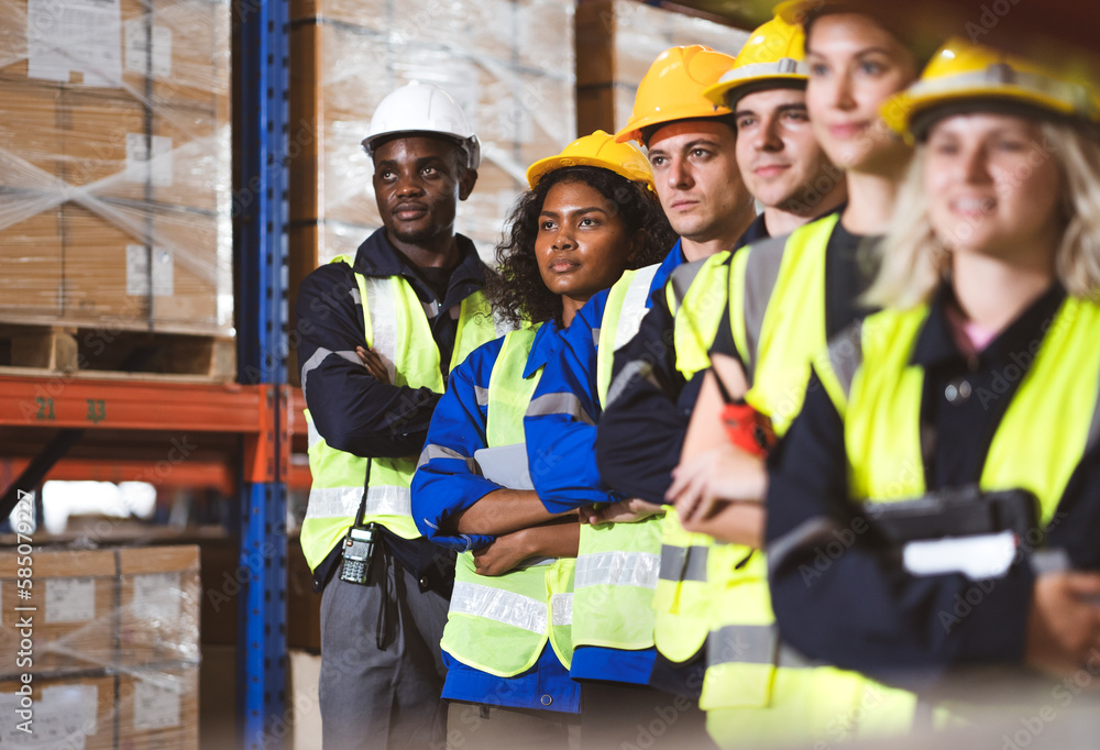 Multiracial group of men and women workers standing in merchandise storage warehouse in factory. Multiethnic people and colleagues working together, portrait. Diverse people teamwork. Selective focus Multiracial group of men and women workers standing in merchandise storage warehouse in factory. Multiethnic people and colleagues working together, portrait. Diverse people teamwork. Selective focus