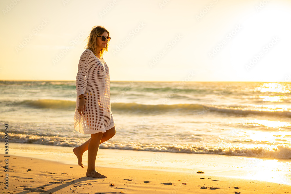 Beach holiday - beautiful woman walking on sunny, tropical beach
