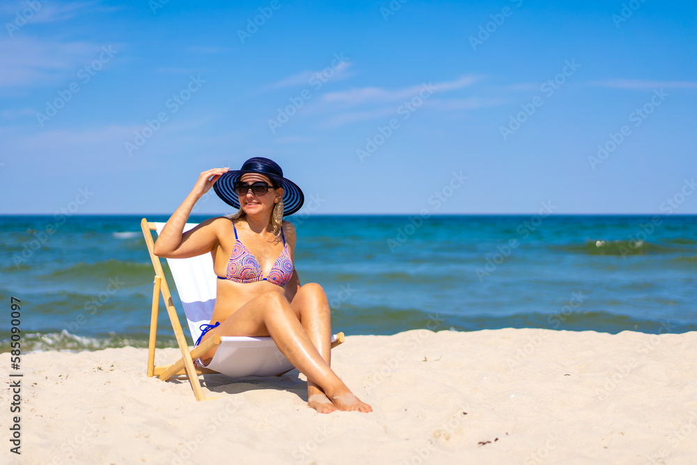 Woman relaxing on beach sitting on sunbed
Woman relaxing on beach sitting on sunbed