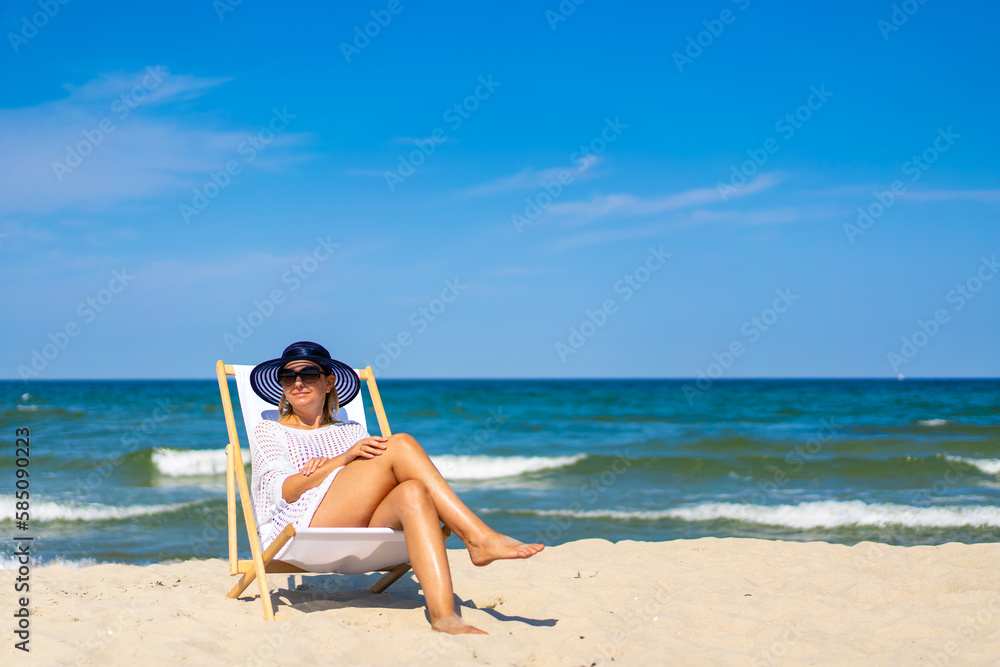 Woman relaxing on beach sitting on sunbed
Woman relaxing on beach sitting on sunbed