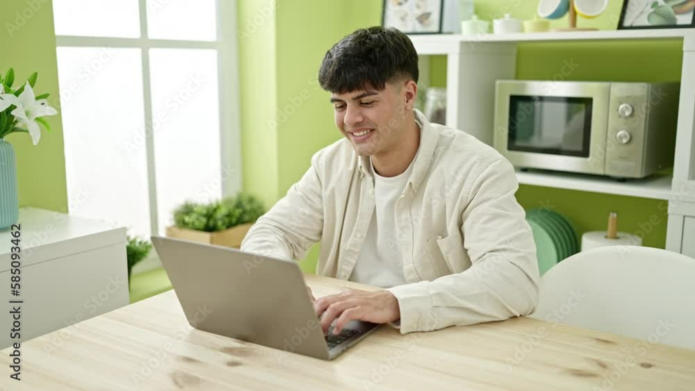 Young hispanic man using laptop sitting on table at dinning room Young hispanic man using laptop sitting on table at dinning room