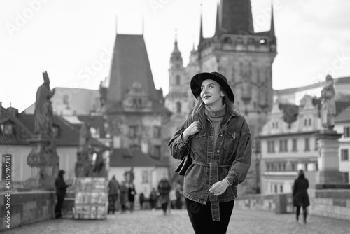 Female traveller tourist on the Charles Bridge in Prague, Czezh Repubic. Stylish beautiful young woman earing black hat. Elegant retro black and white portrait.