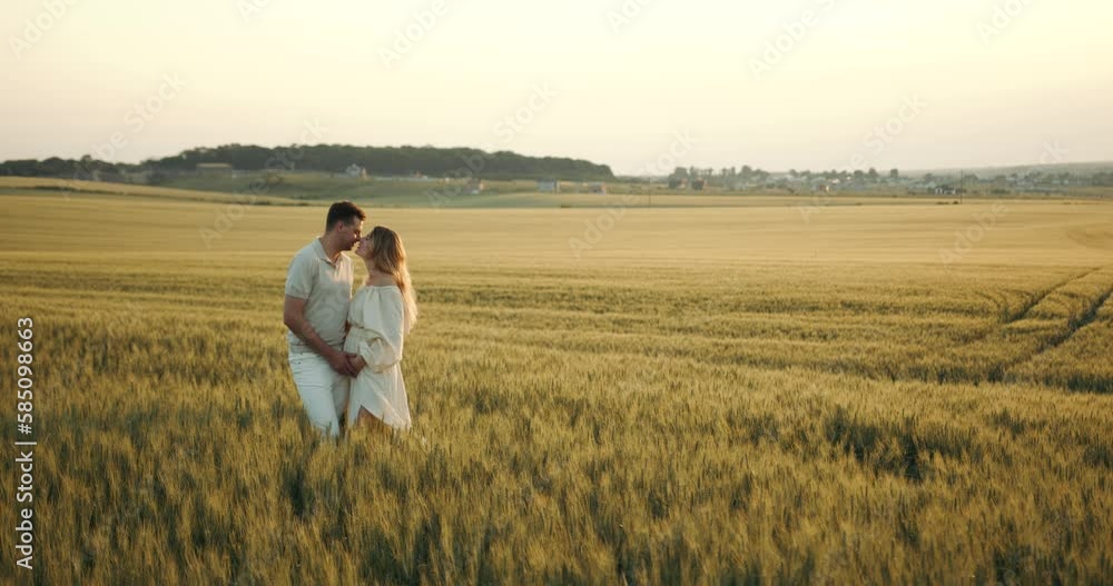 Pregnant woman standing with her husband hugging in the field Pregnant woman standing with her husband hugging in the field