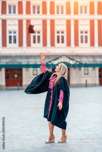 forty-year-old happy woman in a graduation gown walking around the city center.  Study at any age © Iryna