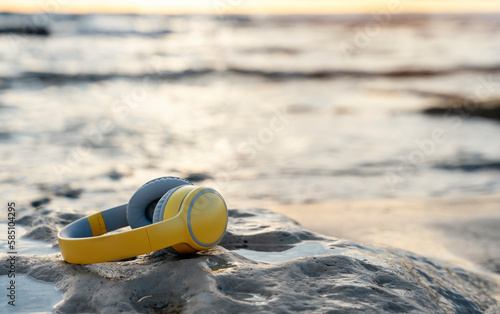 Headphones  on the beach on the sand near the sea at sunset.  Take music or book on a journey, listen to the music of nature. Copy space