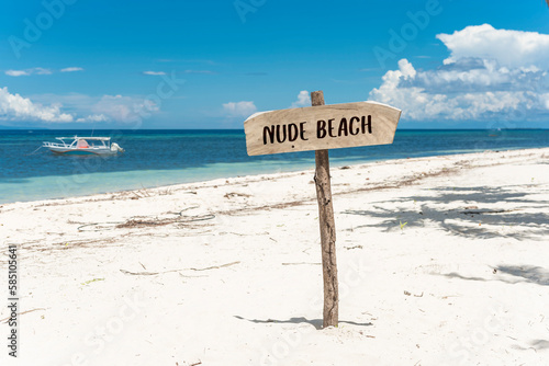 A nude beach sign posted at the beachfront. A nudist beach or naturist resort. photo