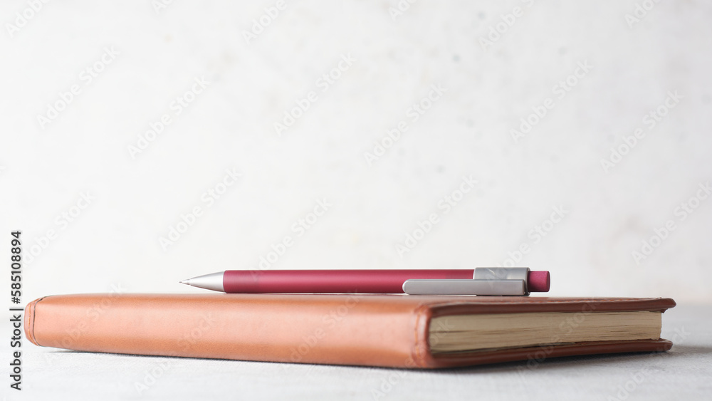 pencil on a note book or leather diary placed on white table top against a textured wall background, education and journaling concept with copy space and soft-focus pencil on a note book or leather diary placed on white table top against a textured wall background, education and journaling concept with copy space and soft-focus