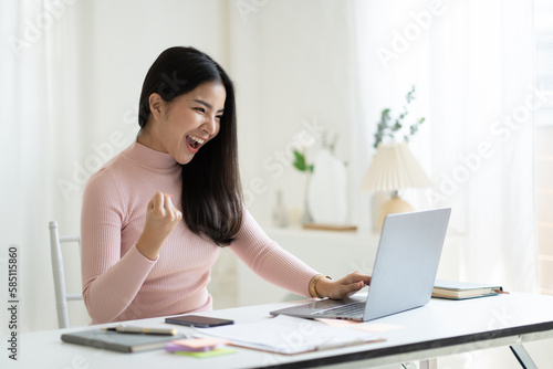Beautiful Asian girl celebrate with laptop computer after receive good news from work.