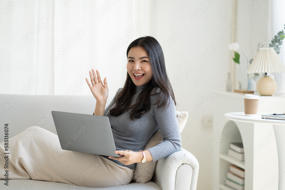 Cheerful young asian woman having a video call while sitting on the couch. Cheerful young asian woman having a video call while sitting on the couch.