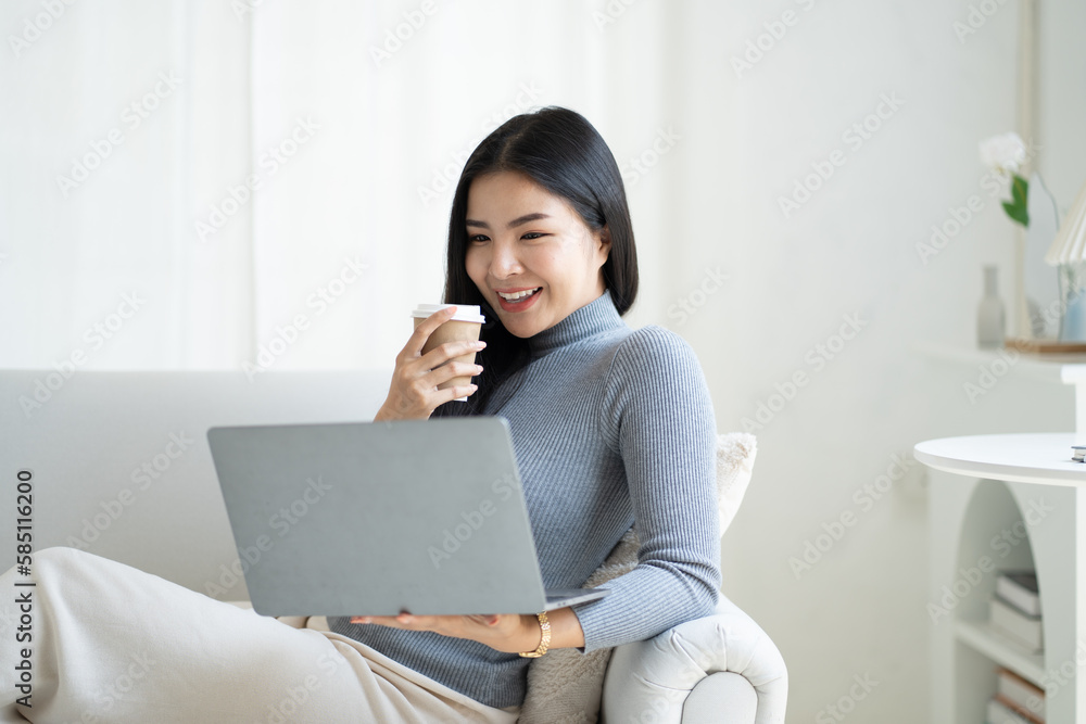 Pretty Asian woman having a relax time drinking a coffee and using laptop. Pretty Asian woman having a relax time drinking a coffee and using laptop.
