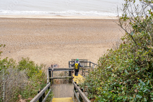 Unidentifiable woman desceding the steps to the stony beach photo