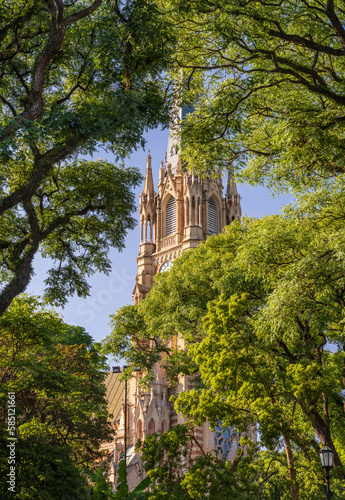 Leafy view of the tall church spire and clock tower of San Isidro cathedral near Buenos Aires in Argentina