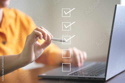 Business performance checklist concept, businessman using laptop doing online checklist survey, filling out digital form checklist. photo