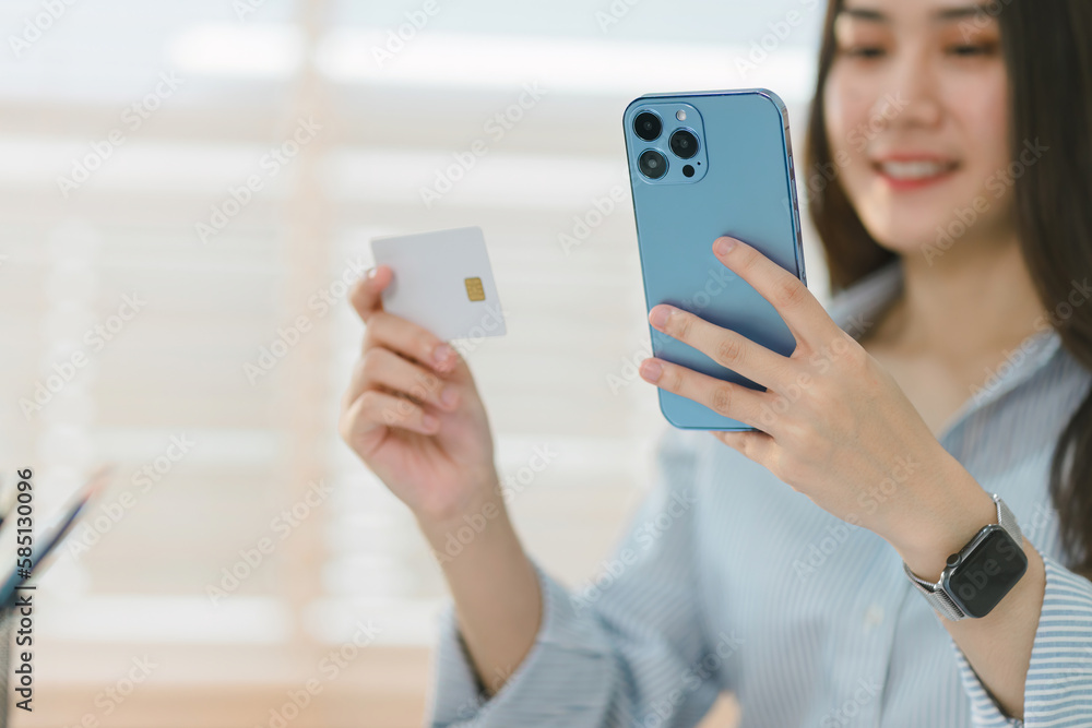 Cropped shot of happy young woman is shown shopping online using her laptop and credit card at home.