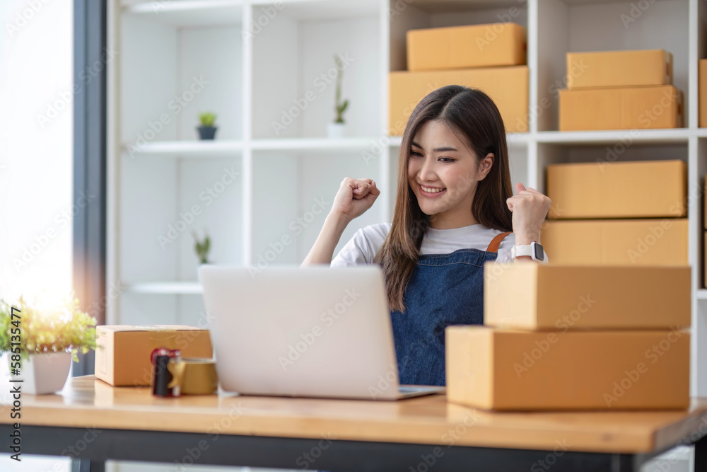 A portrait of a young Asian woman, e-commerce employee sitting in the office full of packages in the background write note of orders and a calculator, for SME business ecommerce and delivery business.