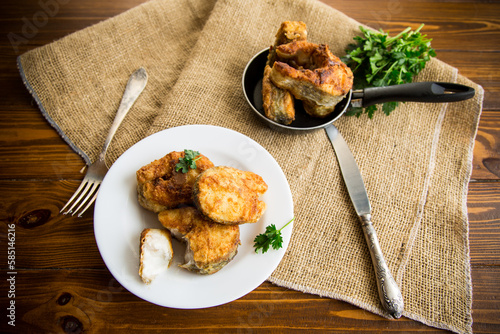 A piece of hake fish fried in a crispy crust, in a plate. photo